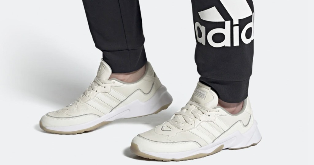 person in black adidas sweatpants wearing white and cream colored adidas sneakers