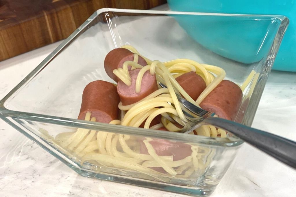 A bowl of noodles and hot dogs