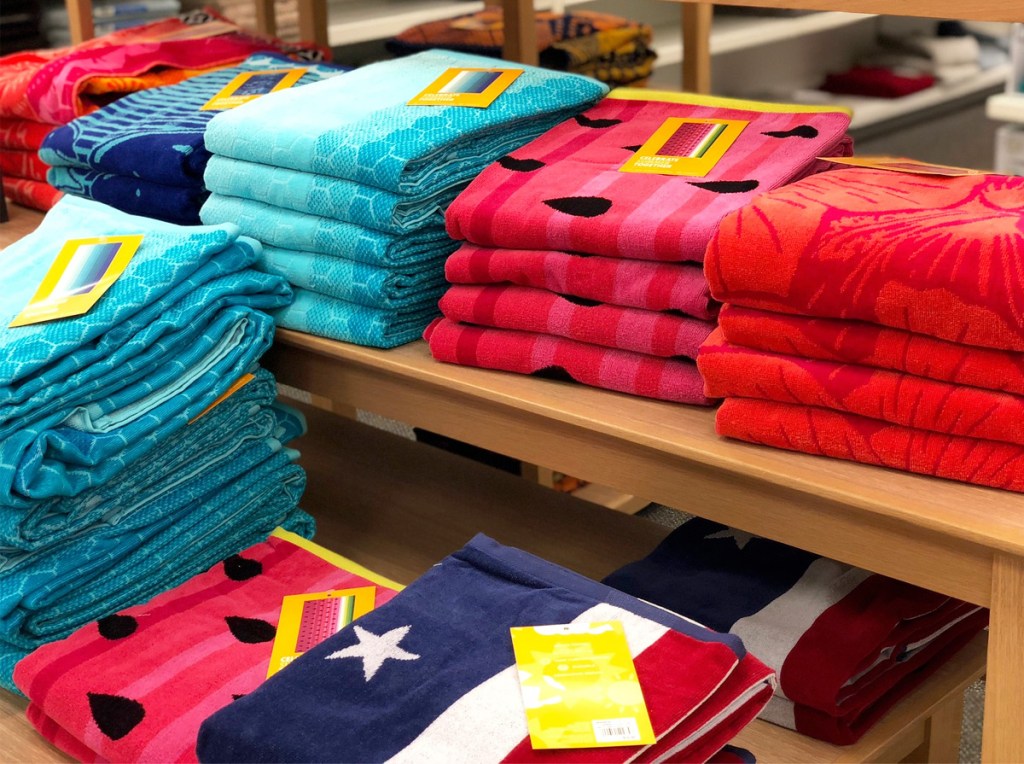 store display table full of folded beach towels in different prints