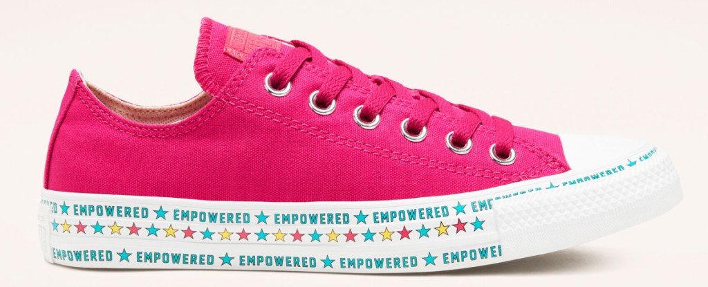 pink canvas converse shoe with white rubber toe and sole that has the word "empowered" printed along it