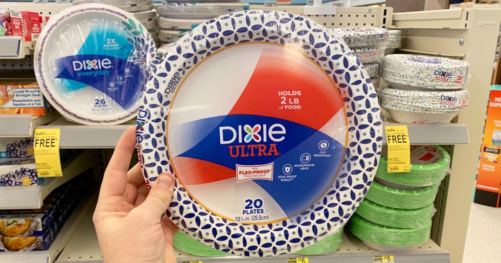 person holding up a pack of dixie paper plates in front of shelf of other paper plates