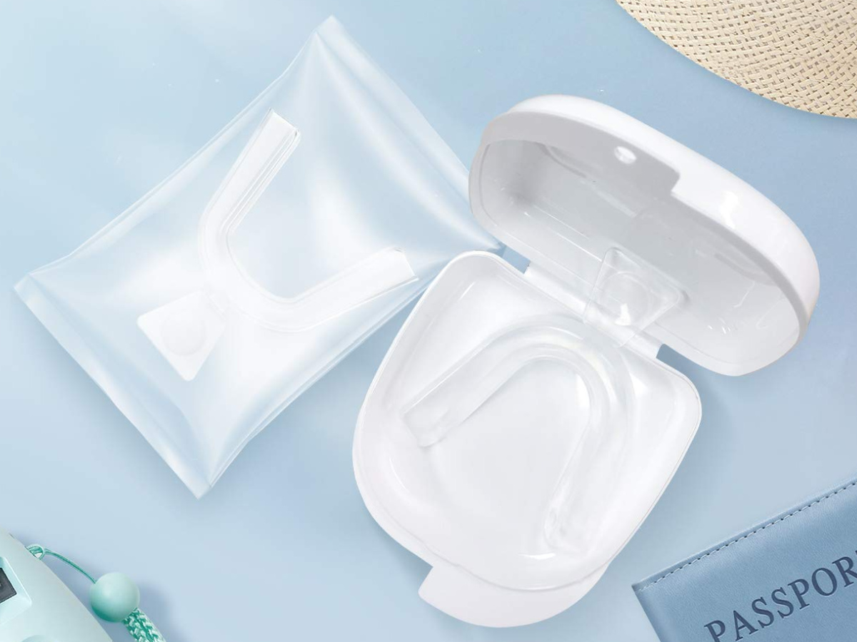 mouth guard in package next to white mouth guard case on light blue surface