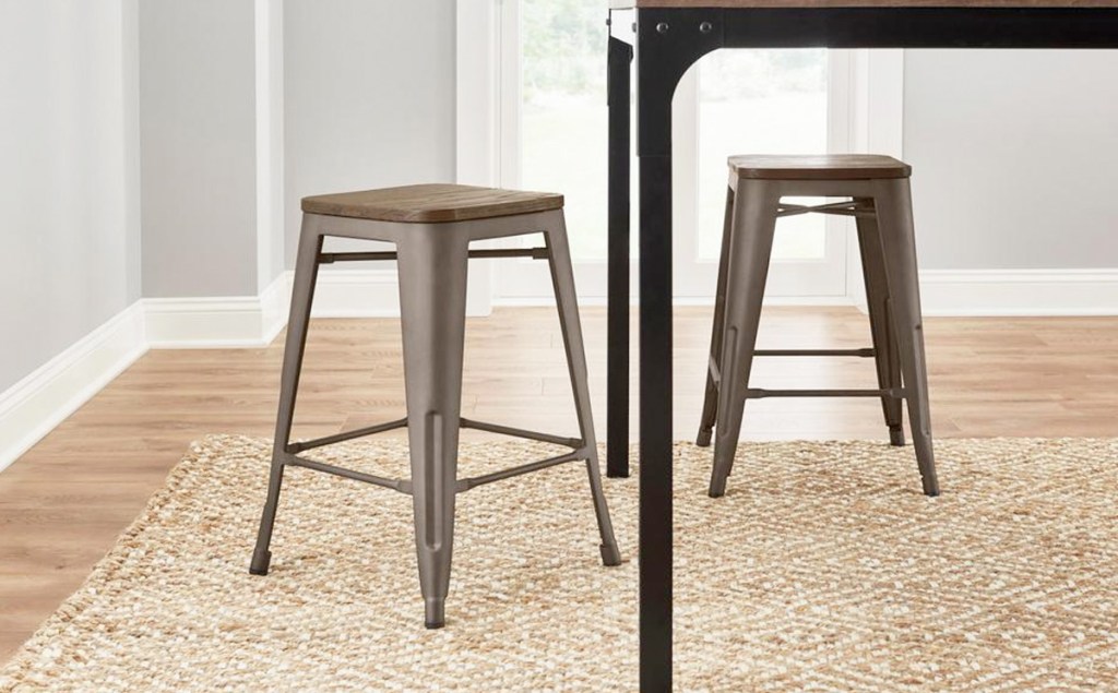 two brown metal backless barstools with wooden seats