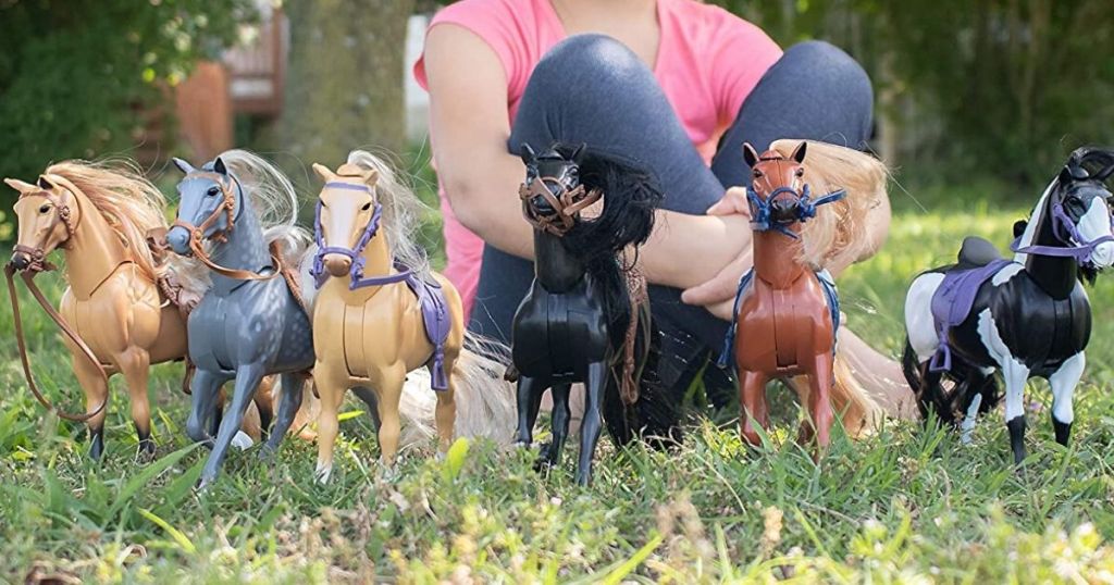 Horse toys lined up in front up in front a little girl