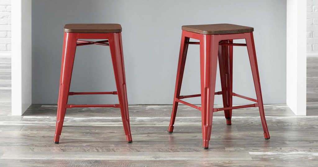 two red metal backless barstools with wooden seats