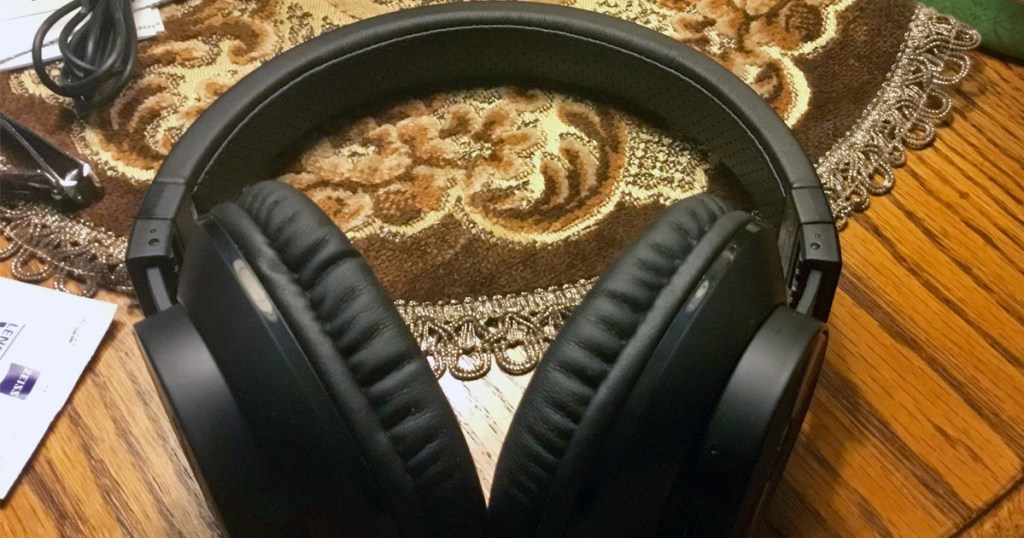 black pair of over-the-ear headphones on a wood kitchen table