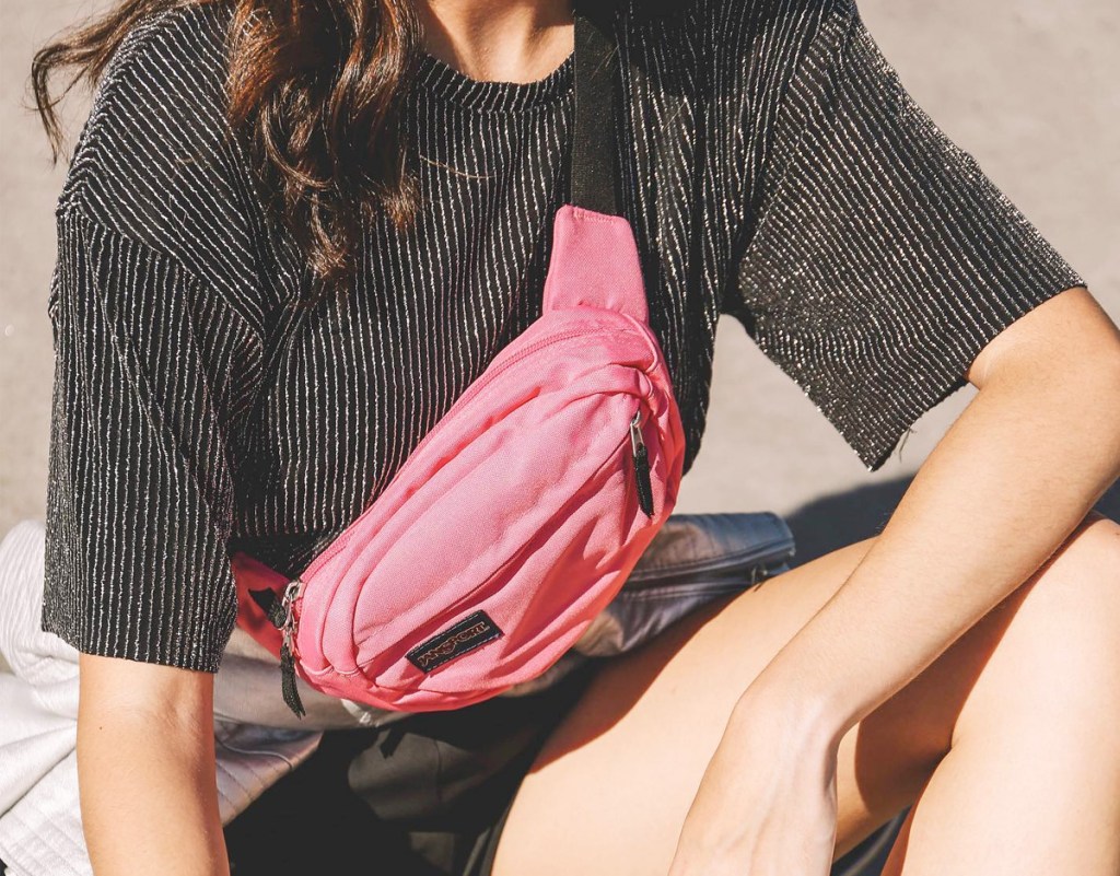 woman in grey shirt wearing a pink fanny pack as a crossbody bag