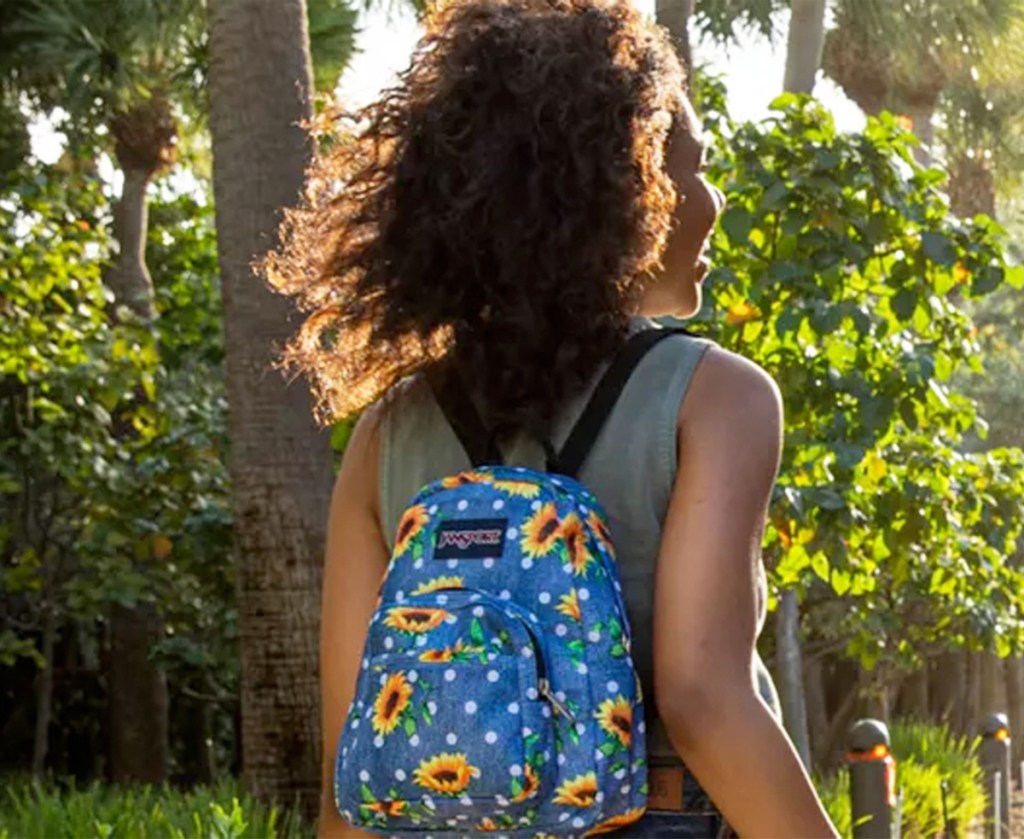 woman wearing a blue mini packpack with sunflower and white polka dot print