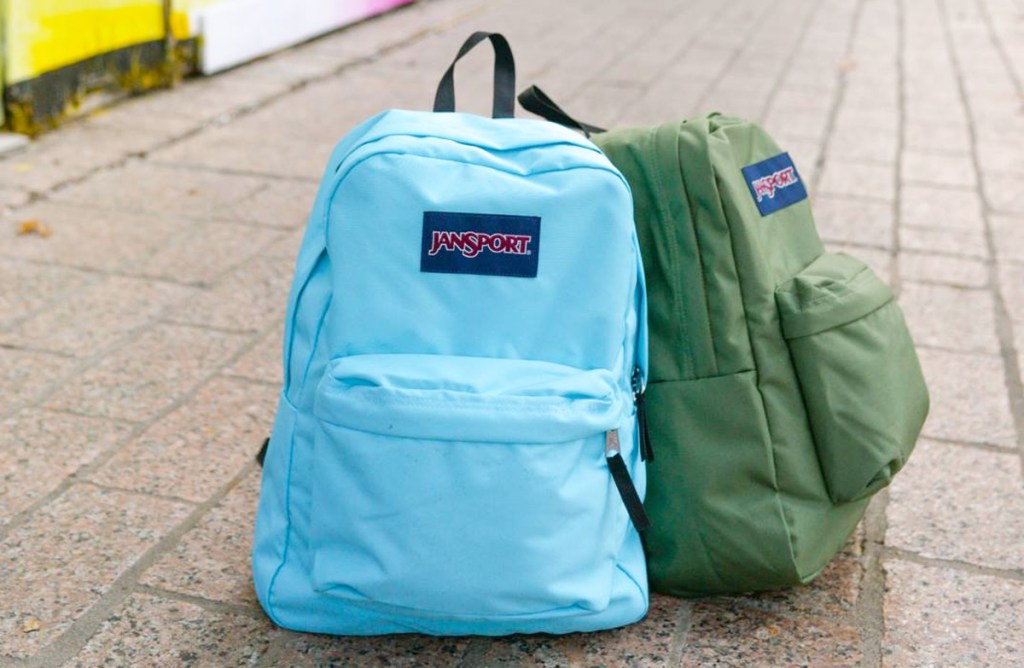 blue and green jansport brand backpacks sitting on sidewalk