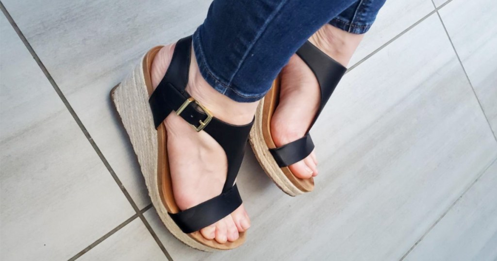 woman wearing a pair of black wedge sandals and skinny jeans
