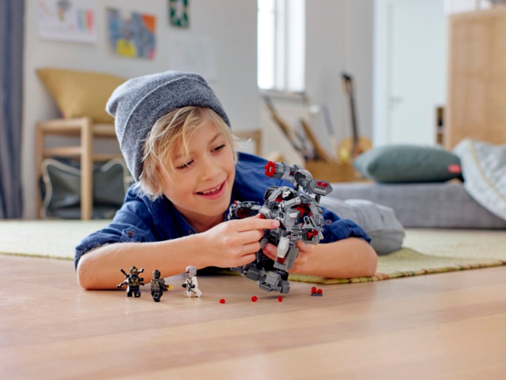 Kid playing with a LEGO Marvel Avengers War Machine Buster Superhero Mech Building Set