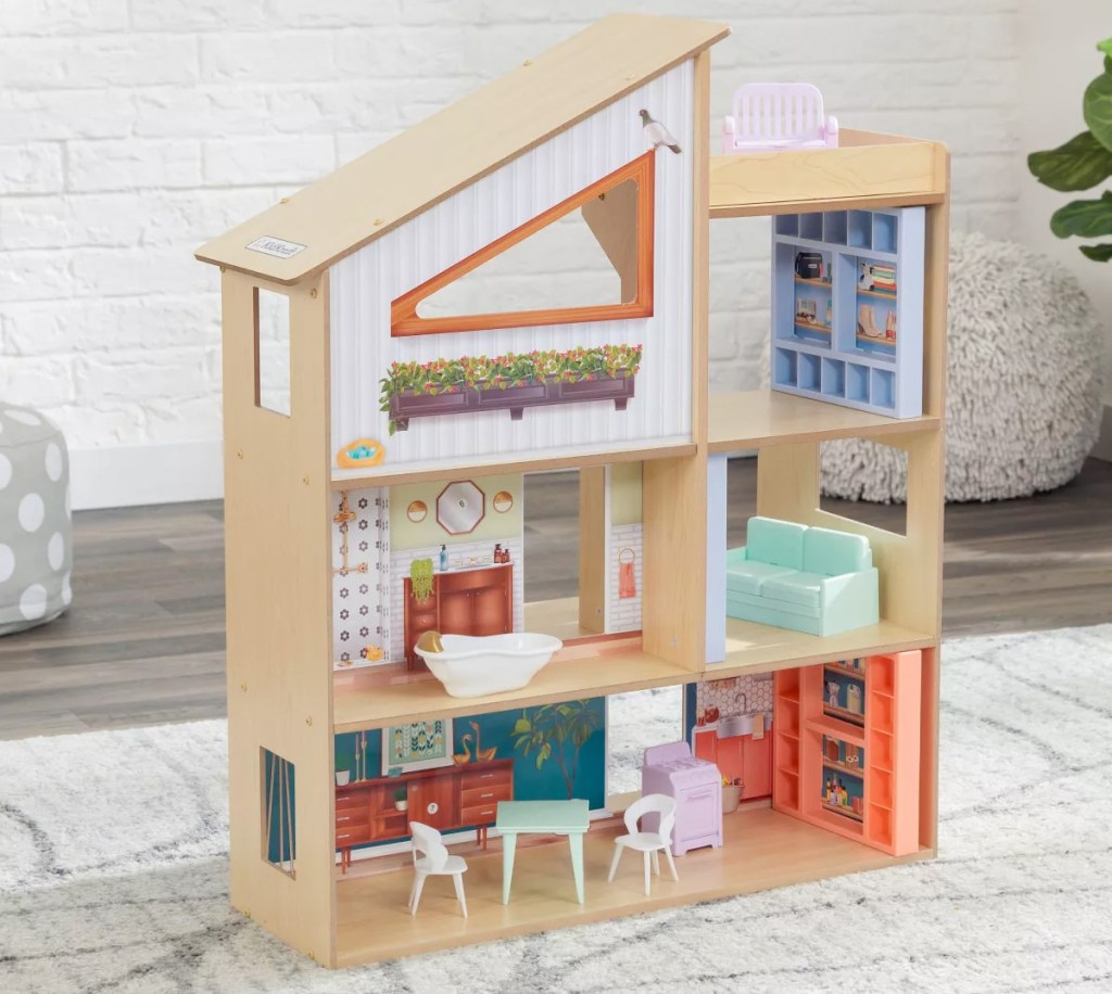 wooden dollhouse sitting on area rug with furniture in each room