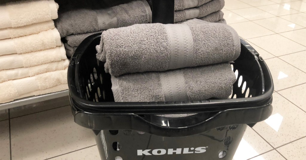 black kohls shopping basket with grey towels inside near display shelf of towels