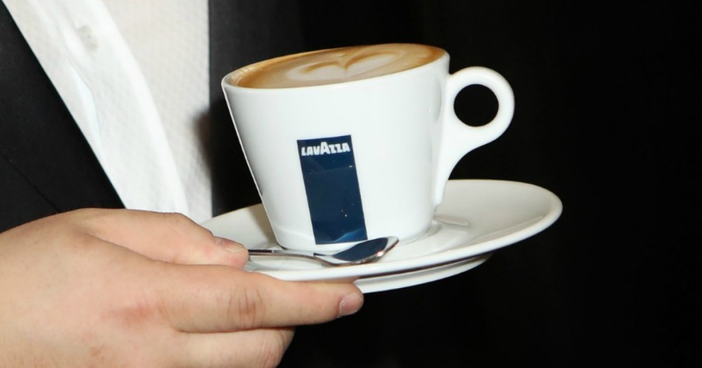 Cup of espresso on a plate being held by a man wearing a suit