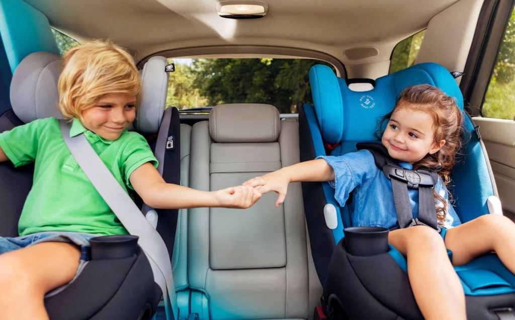kids holding hands sitting in car seats