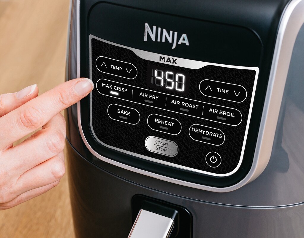 hand touching buttons on an air fryer