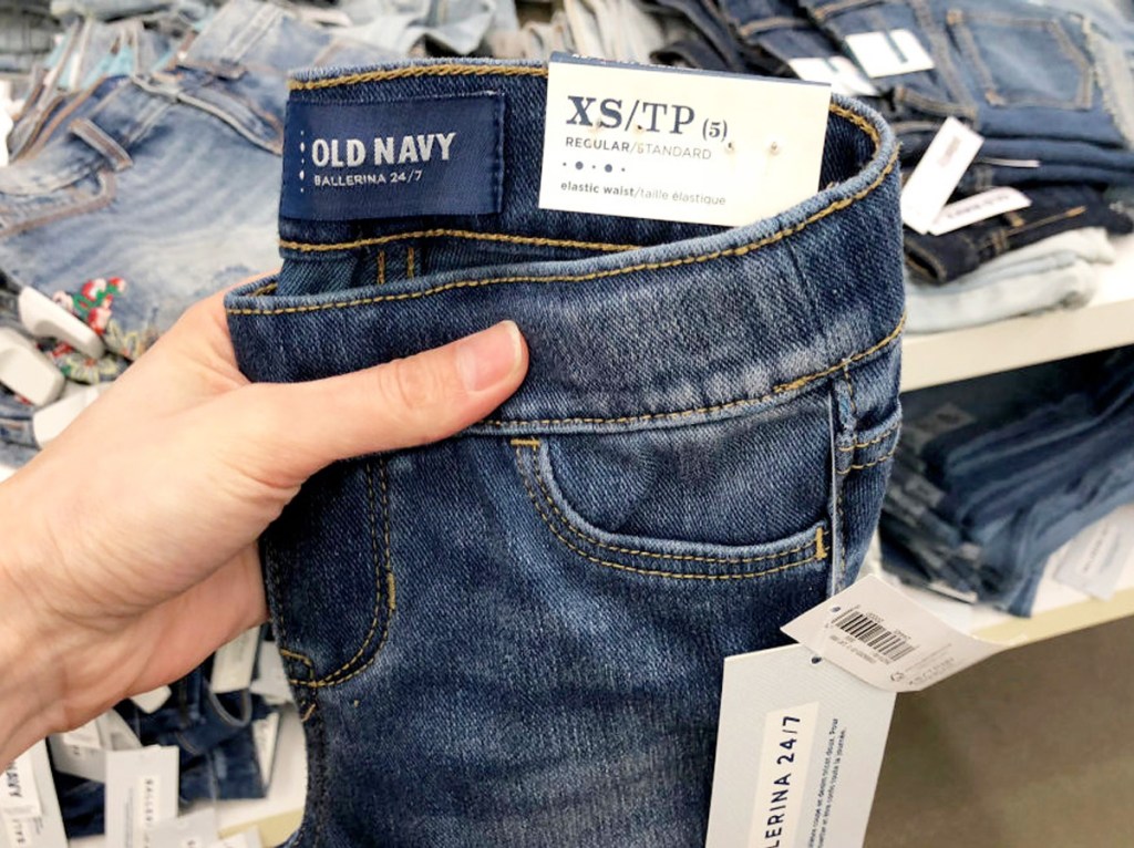 person holding up a pair of dark wash old navy girls jeans