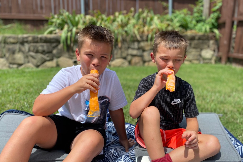 boys trying out orange popsicles