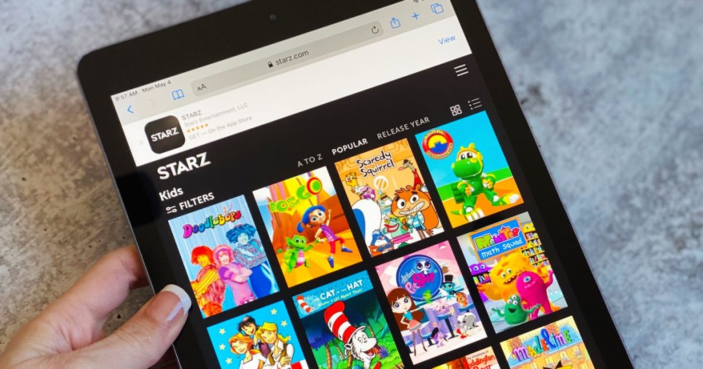 woman holding a black iPad showing the STARZ app and all the available kids shows
