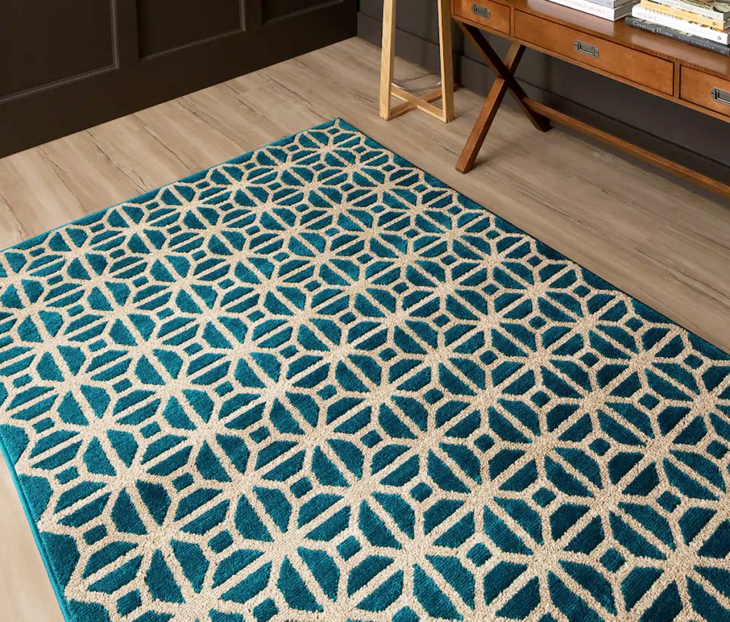 blue and cream colored abstract print area rug on hardwood floor