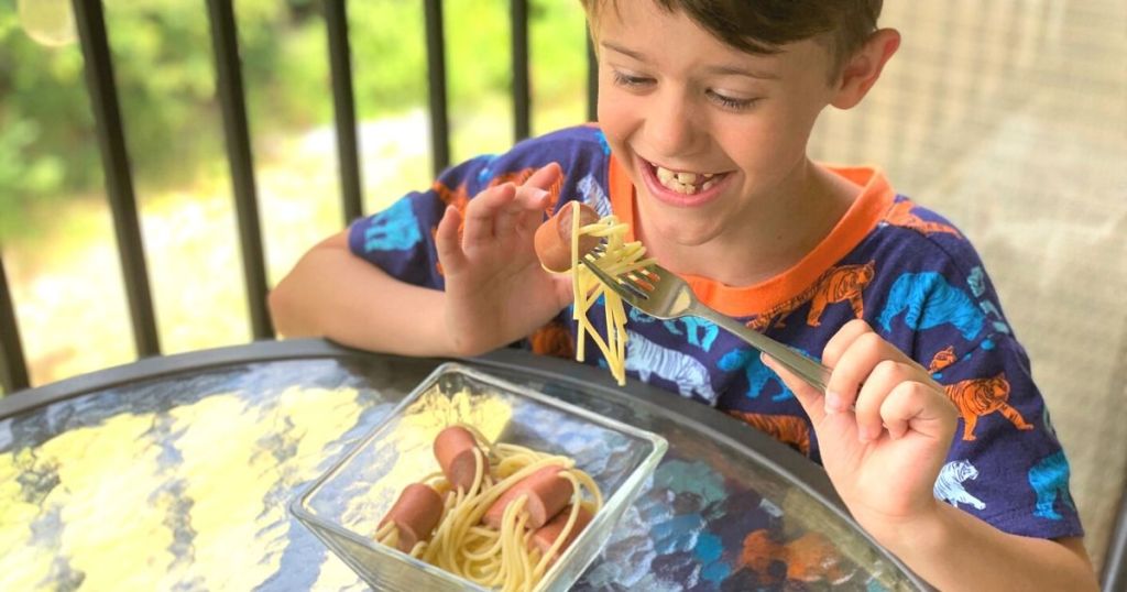 A little boy eating spaghetti at a table