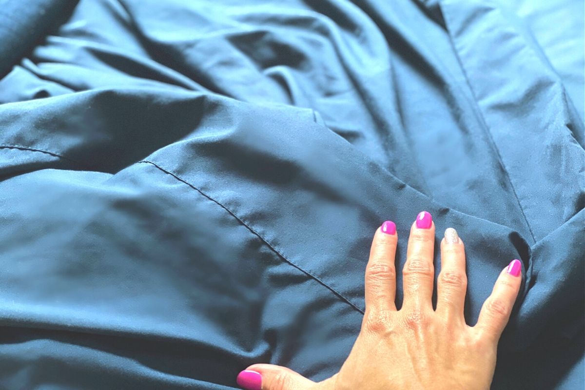 A hand feeling soft sheets on a bed