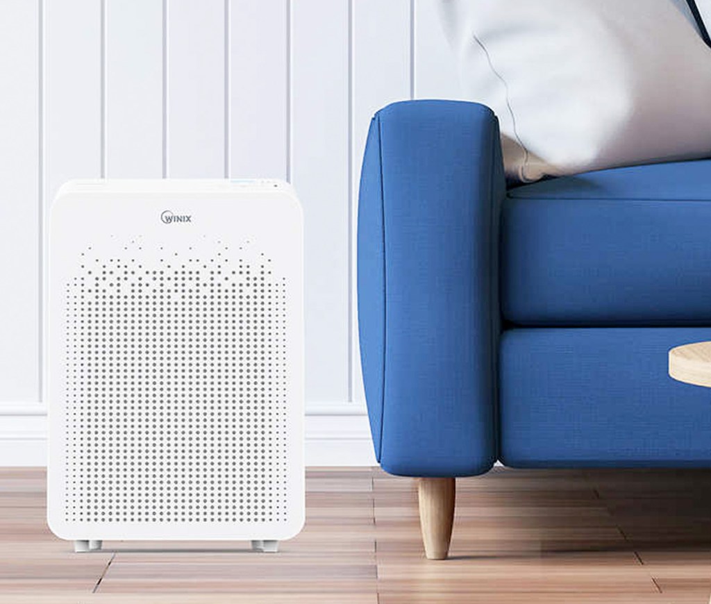 white air purifier on hardwood floor next to blue couch