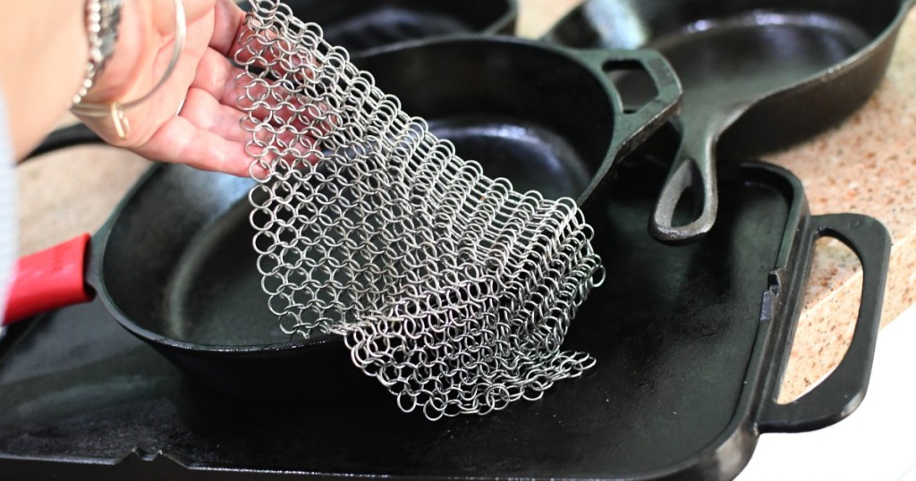 a stack of cast iron pans with a metal scrubber