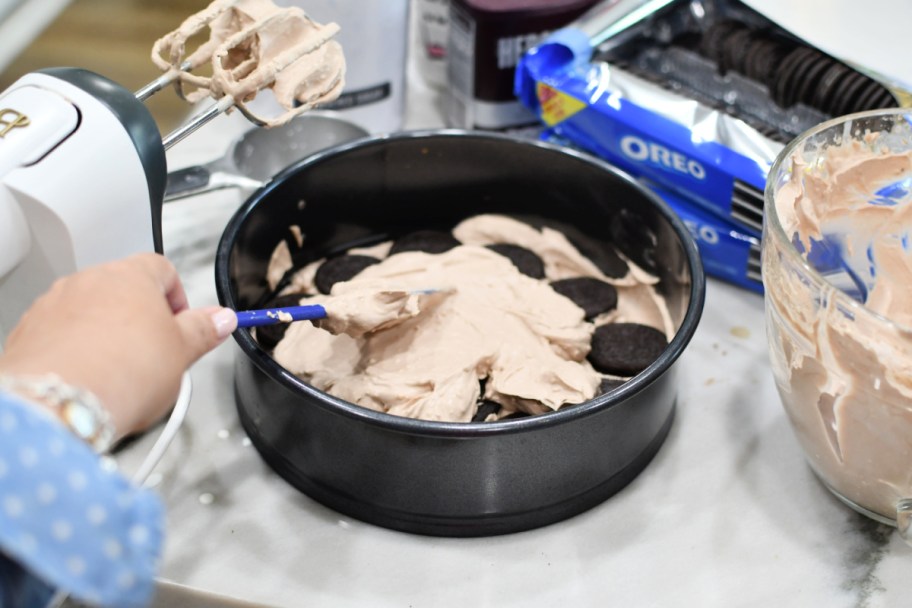 adding second layer of whipped cream to oreo cake
