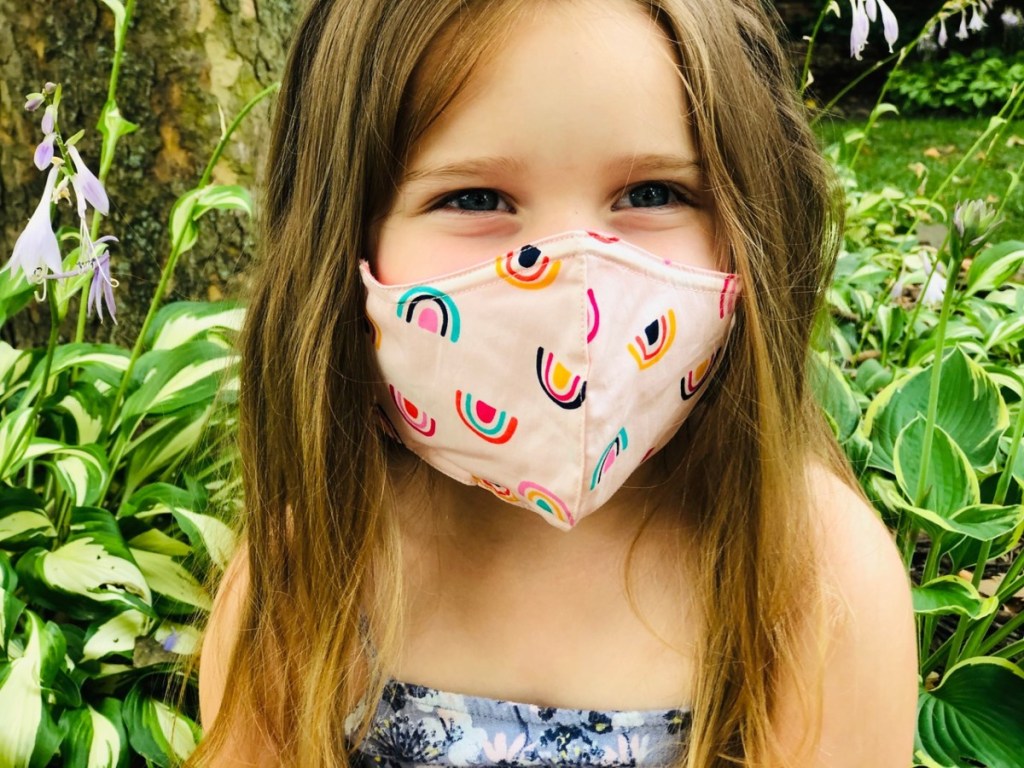 girl wearing pink mask with rainbows