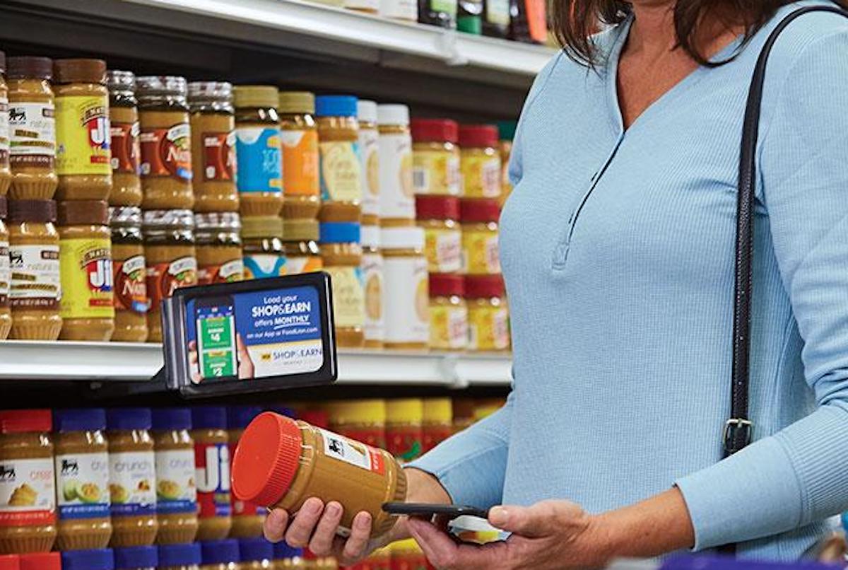 person holding jar of peanut butter in store aisle