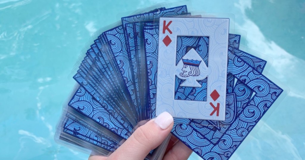 hand holding waterproof playing cards by pool