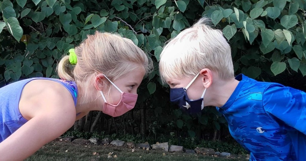 two kids looking at each other in face masks