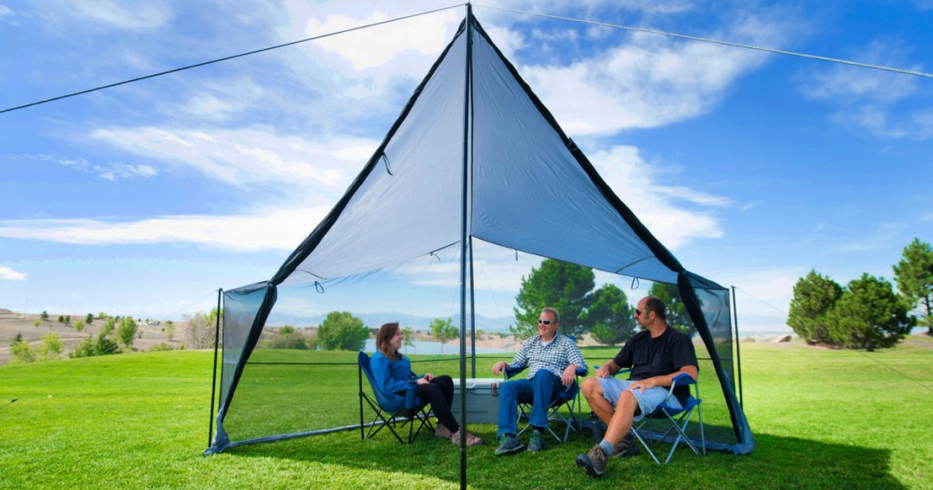 people sitting under a Ozark Trail Tarp Shelter with UV Protection and Roll-up Screen Walls