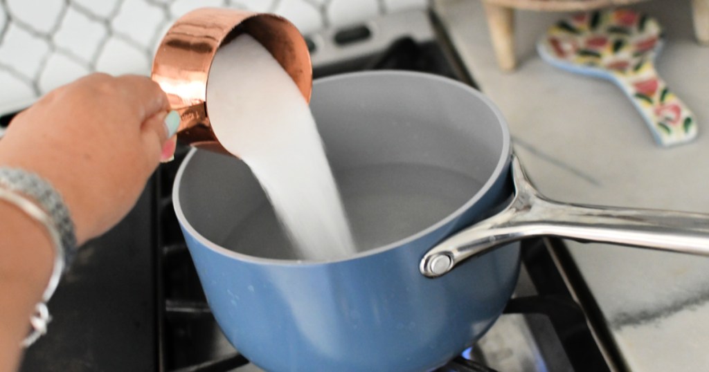 pouring sugar into water to make simple syrup