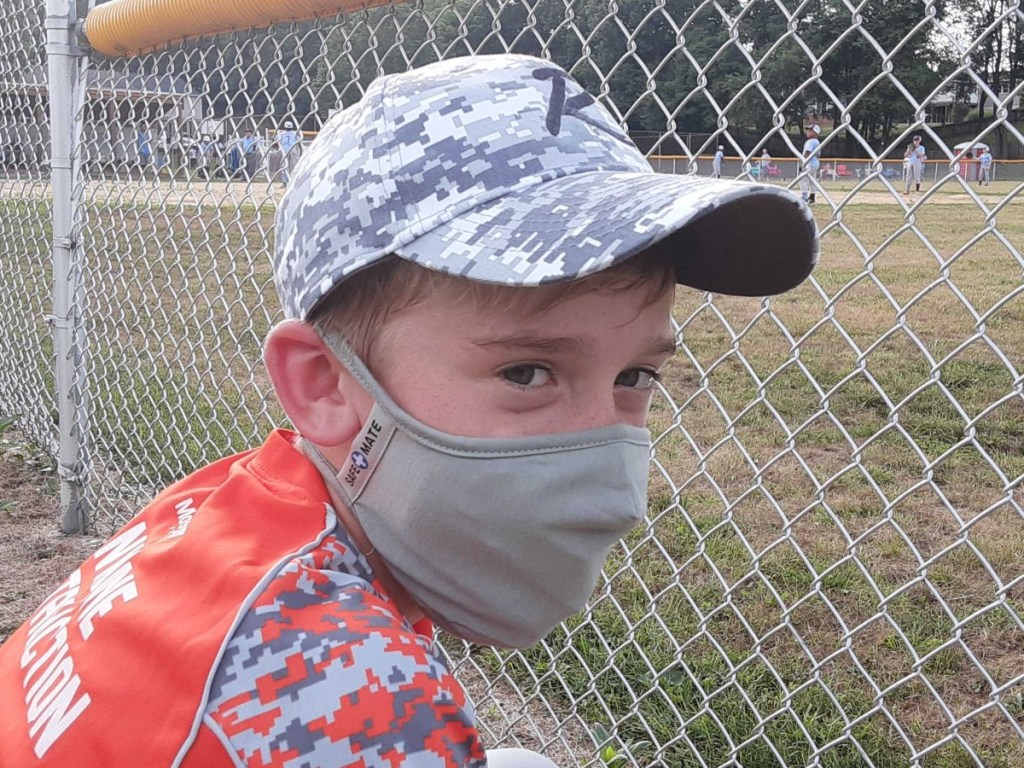 boy wearing baseball hat and gray facemask