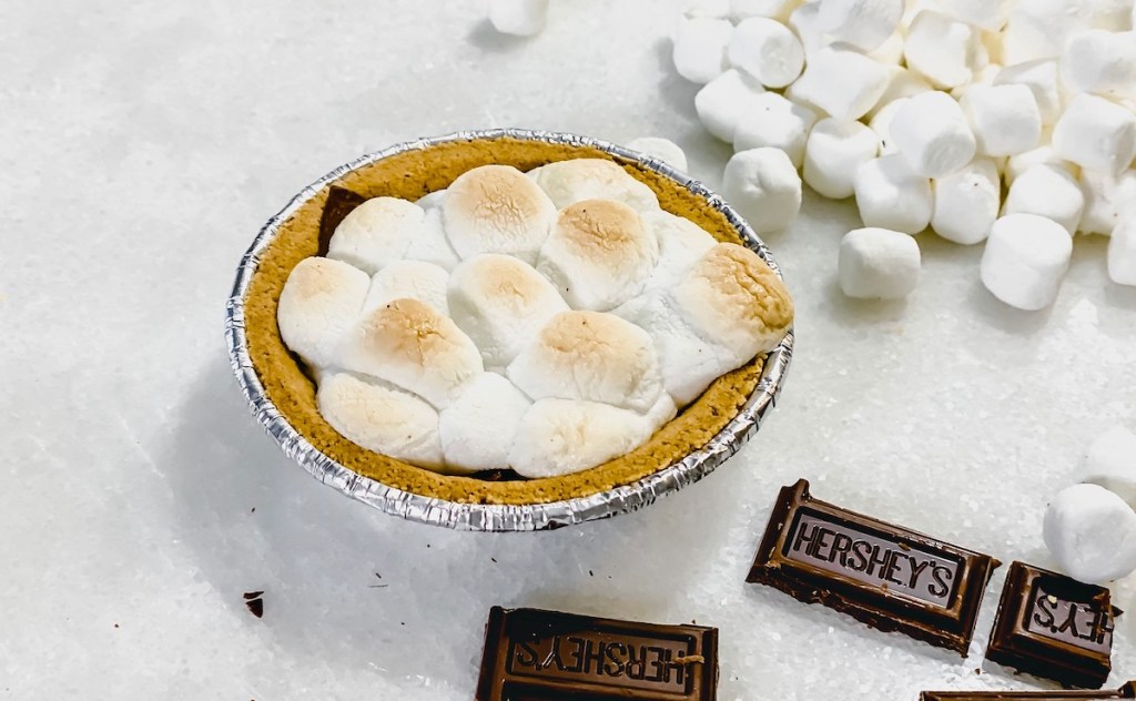 mini smores pie on white counter with hershey's chocolate pieces and mini marshmallows 