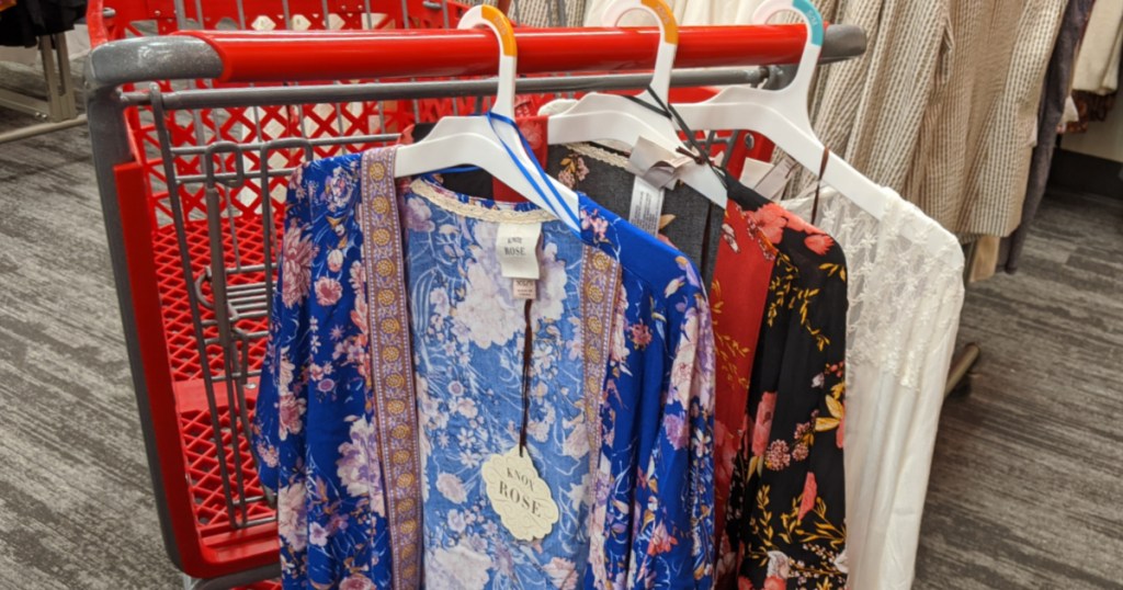 grocery cart with three floral kimonos hanging on it in store