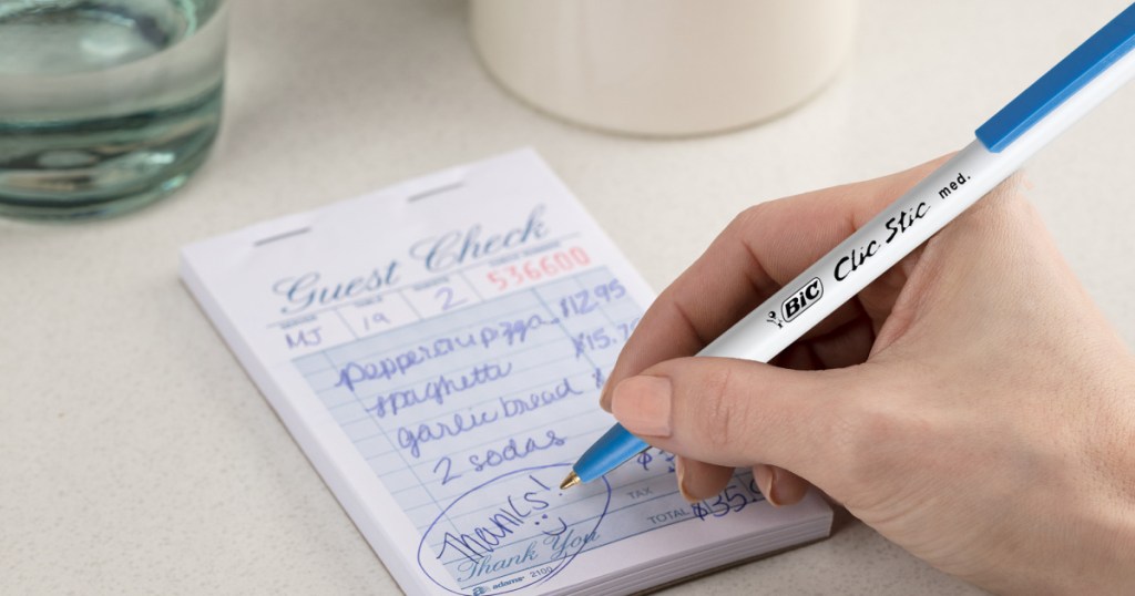 hand holding bic clic pen writing on restaurant pad