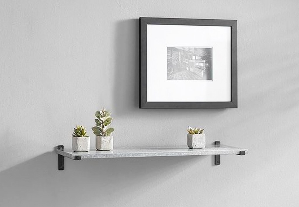 grey floating shelf on wall with succulents on it under a picture frame