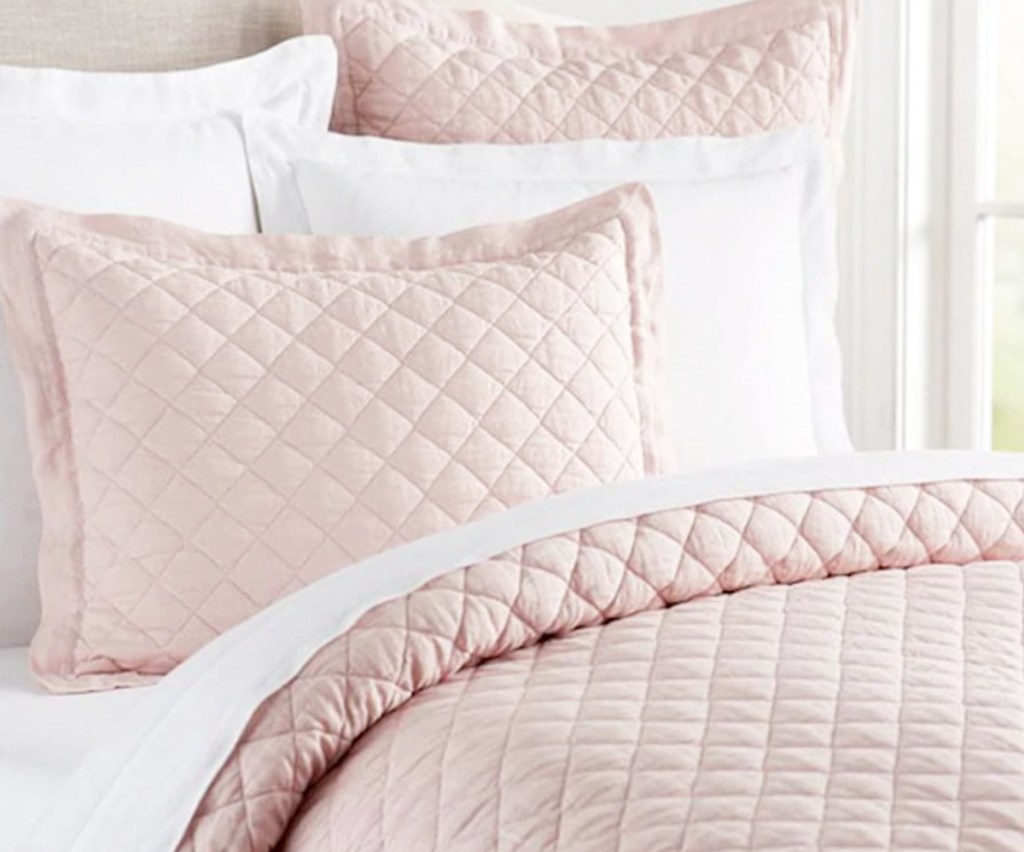 blush pink quilt set on bed with matching pillow shams