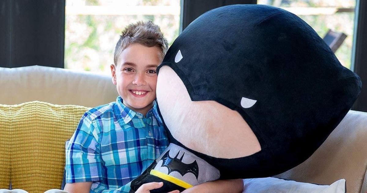 giant head batman toy with little boy on couch