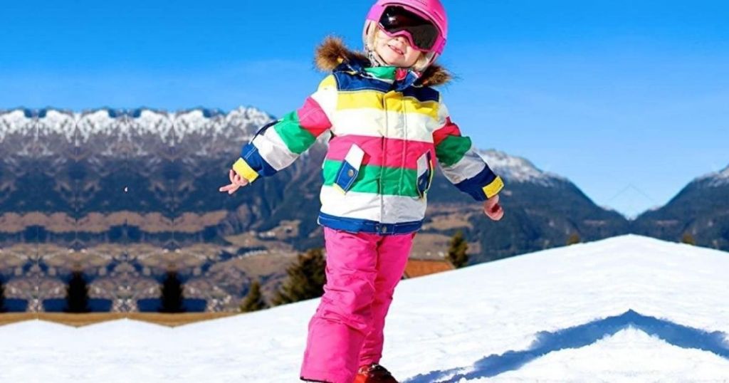 little girl wearing a snowsuit out in the snow