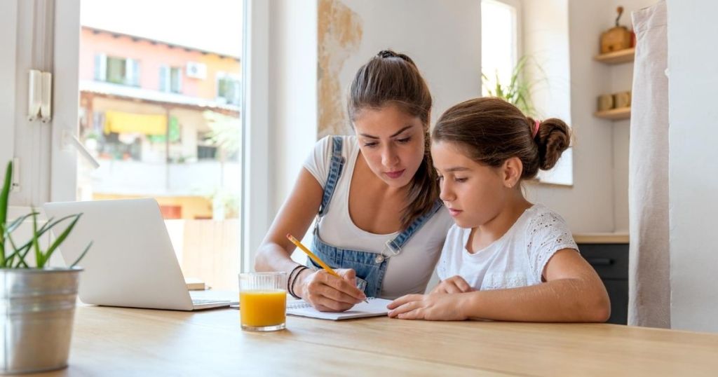 A mom helping daughter with homework at a kitchen table