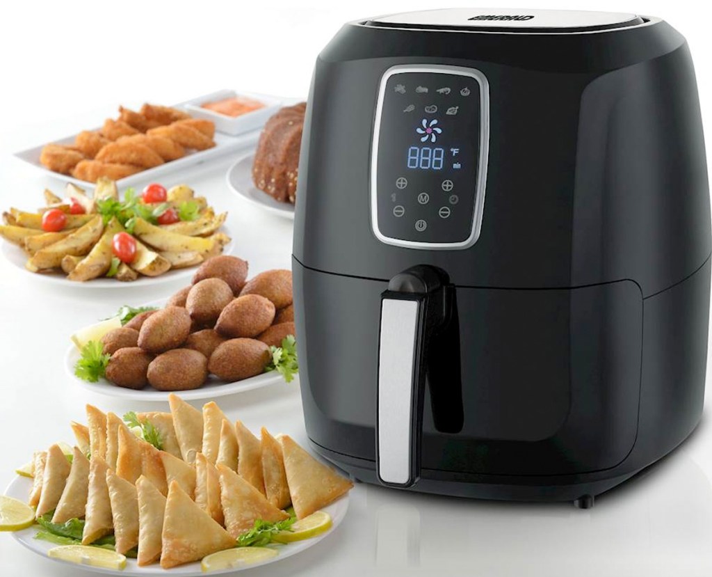 black air fryer with digital controls sitting on counter with plates of fried foods next to it