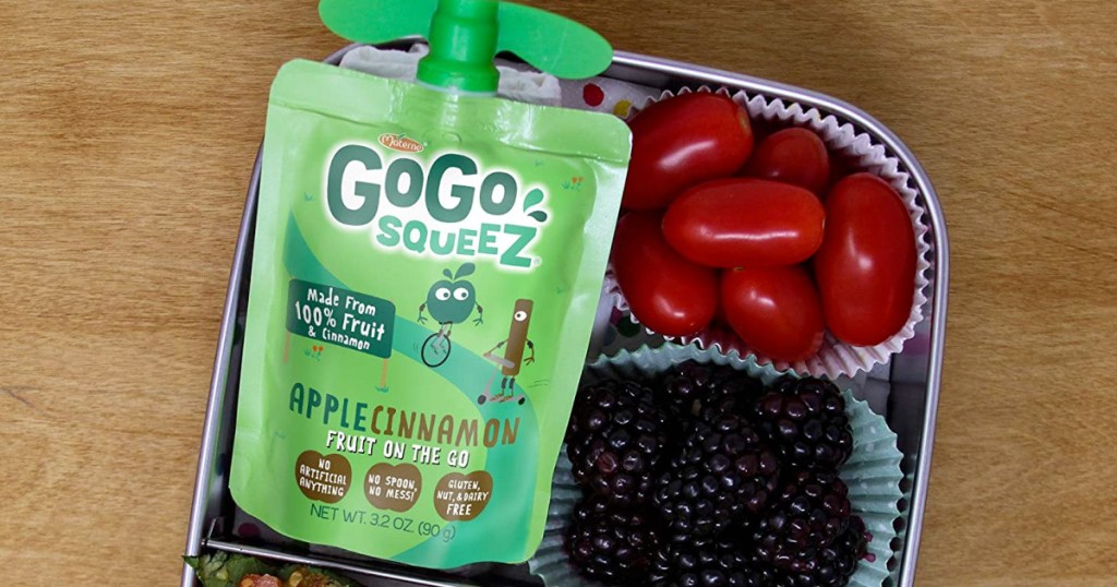 green go-go squeez applesauce packet on a metal lunchbox with blackberries and cherry tomatoes