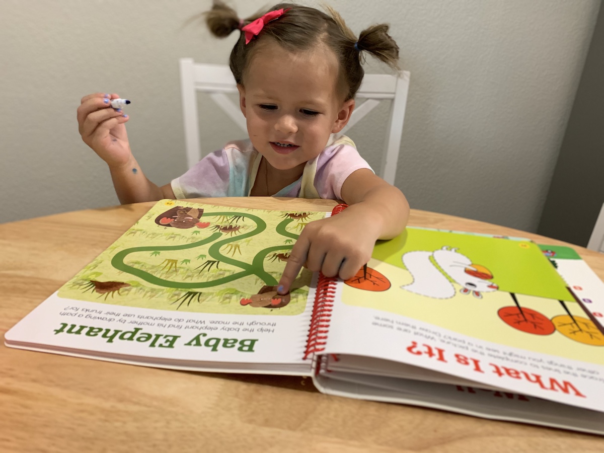 girl pointing to a Highlights workbook