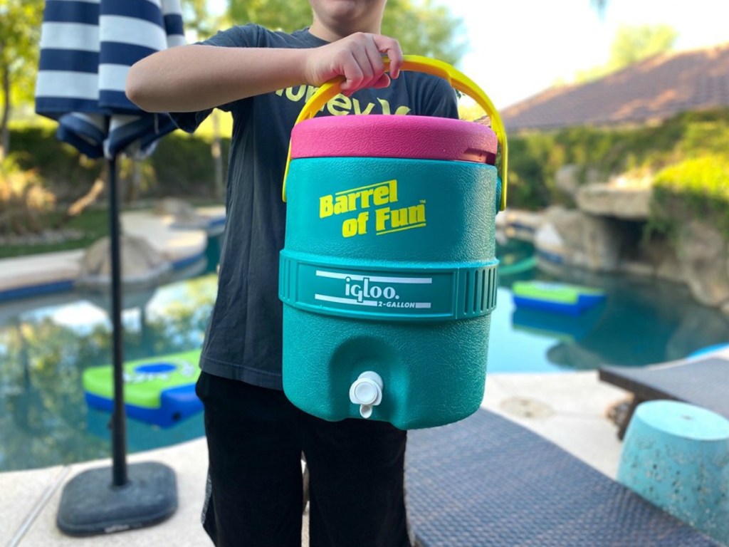 boy holding a igloo cooler by a pool