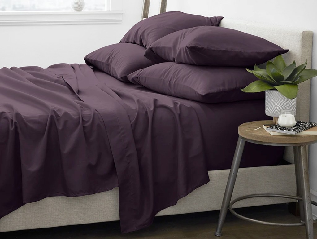 dark purple sheet set on bed with matching pillow shams