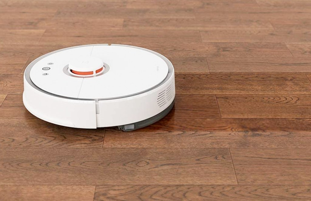 white round robotic vacuum mopping on hardwood floor